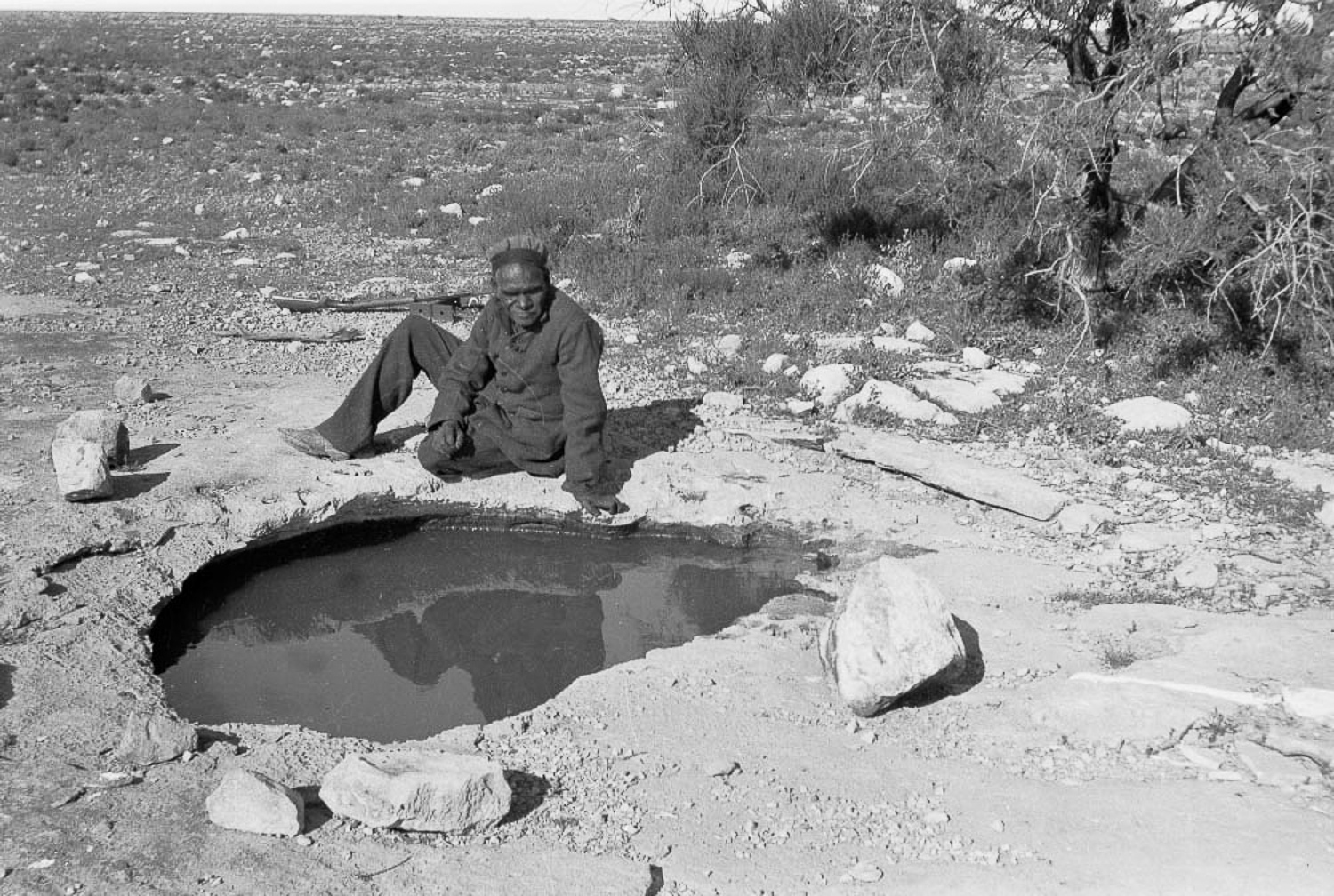 Tracker Jimmie Maadi sits next to the rockhole where Cundeelee mission was based. This water supply was known as Urpulurpulila by Anangu, which means ‘tadpole’ in Pitjantjatjarra language. It was by way of rock holes such as this, as well as other sources of water, that Anangu could survive in the harsh desert climate.