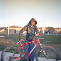 Sudanese boy holding bicycle in suburban Australian street