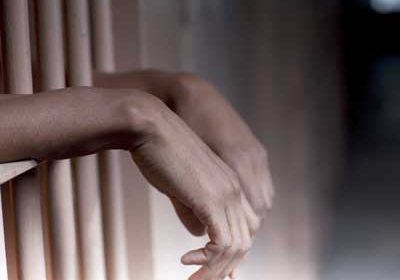 Photo of black hands behind bars