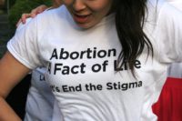 Woman wearing shirt: "Abortion: A Fact of Life. Let's End the Stigma"