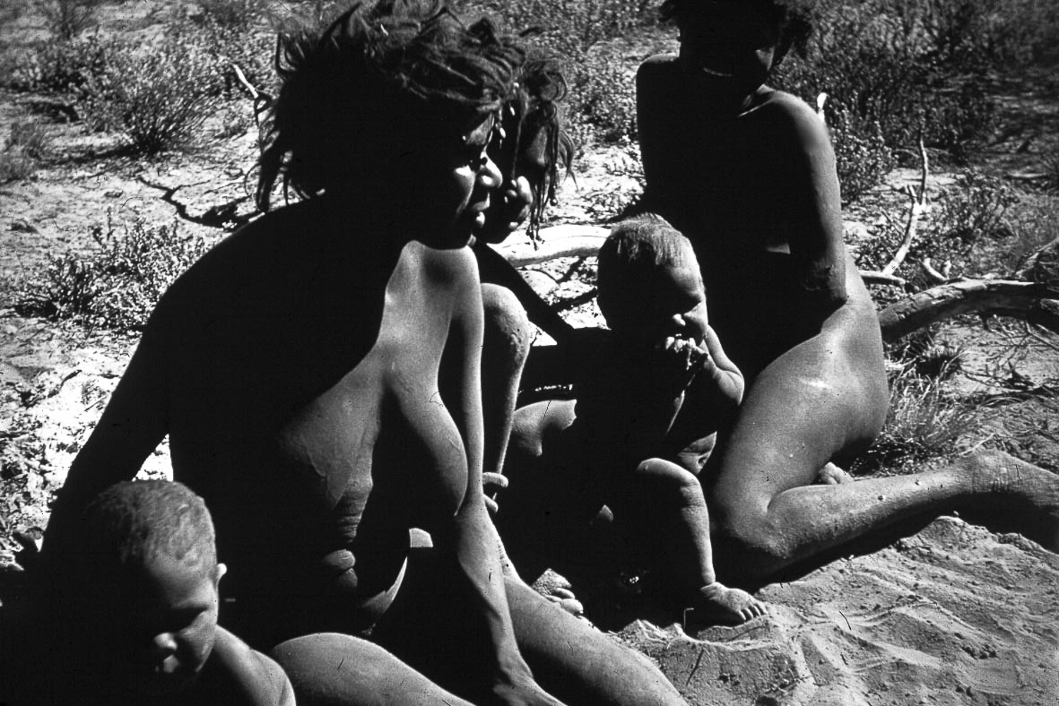 Jessie Walker (front, with children Luana Walker and Marna Walker) with her sisters Carol Walker and Kathleen Donegan at a ration station near present day Tjuntjuntjara, where Anangu would first be taken and given clothes, sugar and flour, prior to being relocated.