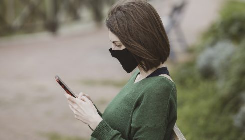 woman in mask using phone